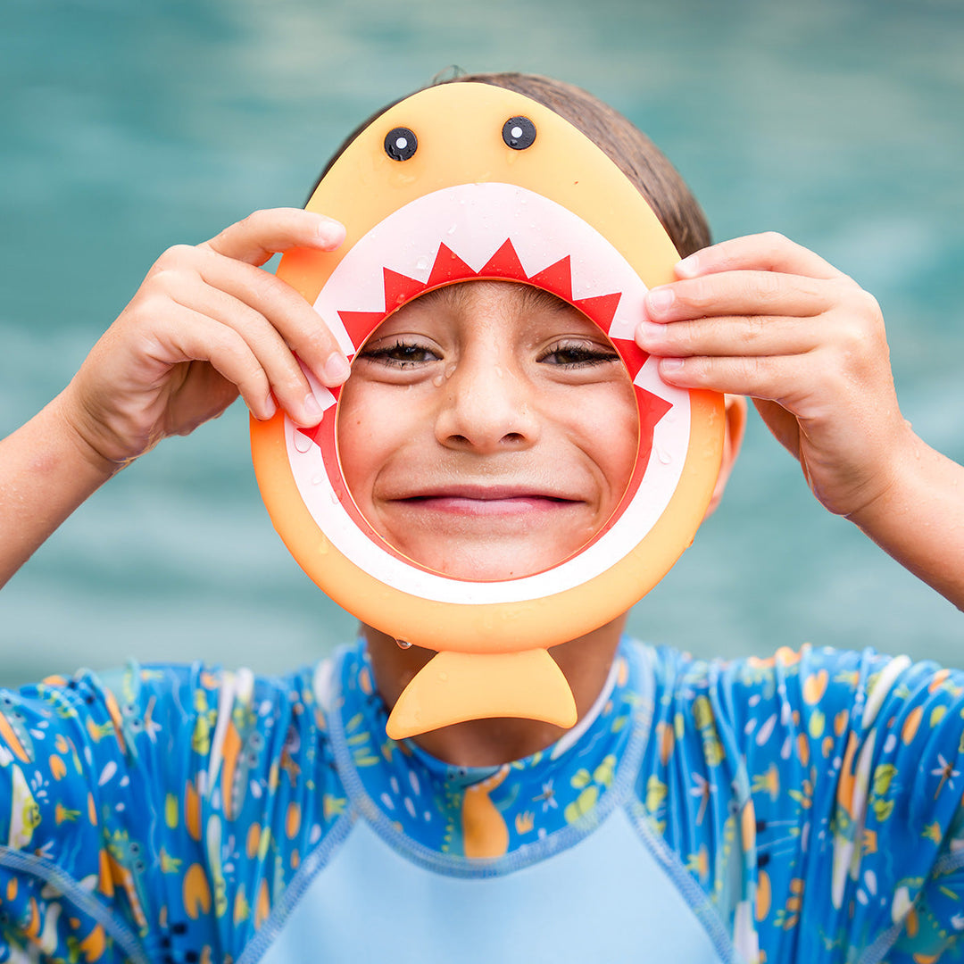 Kid playing with orange shark dive ring