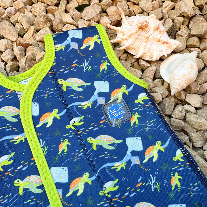 Close up of neoprene baby wrap wetsuit in navy with lime trims and turtles themed print.