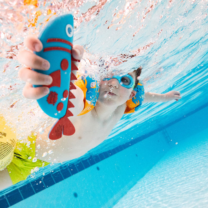Kid playing with a blue and red silicone fish toy in the pool