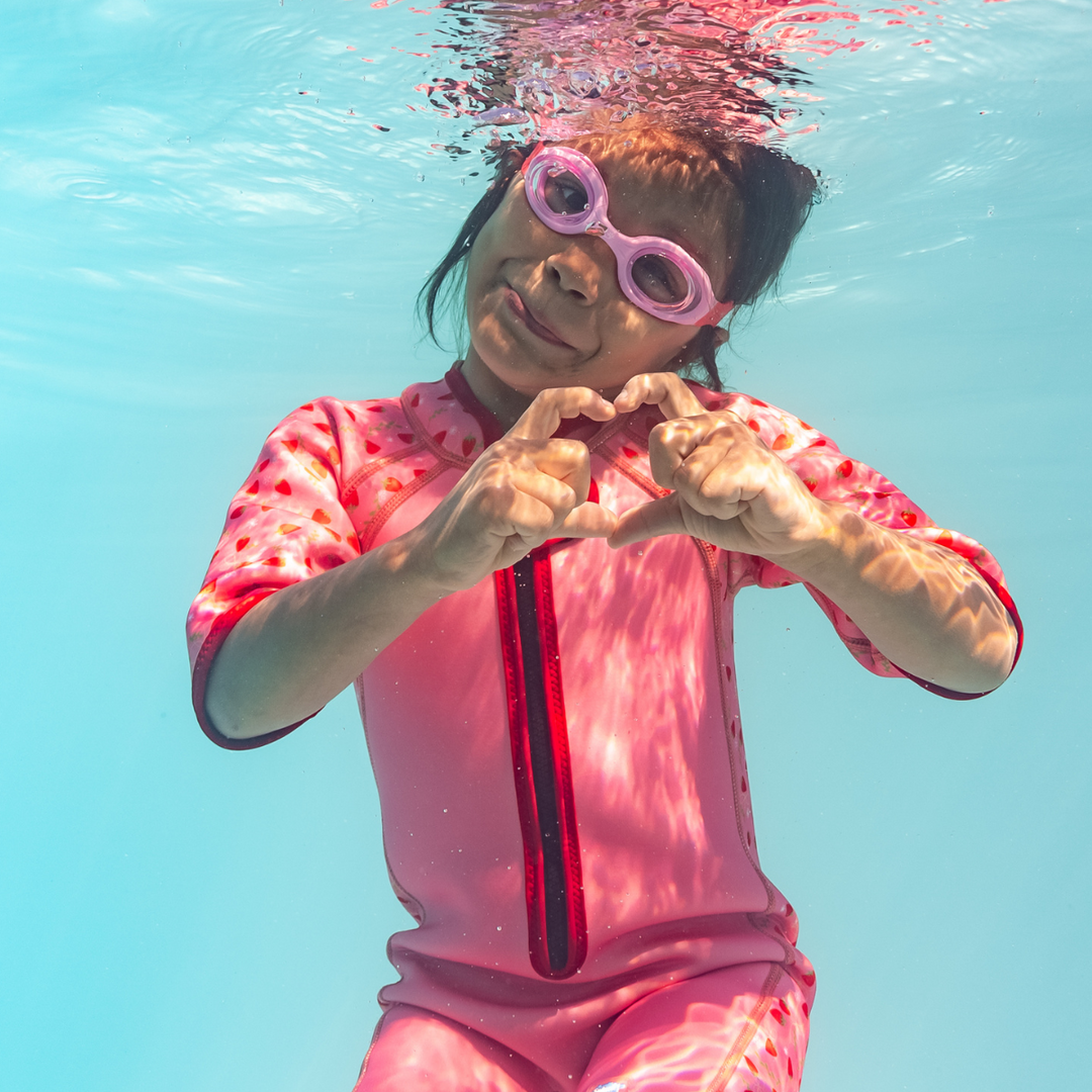 Little one wearing pink goggles underwater