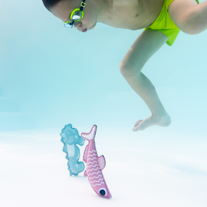 Kid diving to retrieve sardine and seahorse themed neoprene toys in the pool