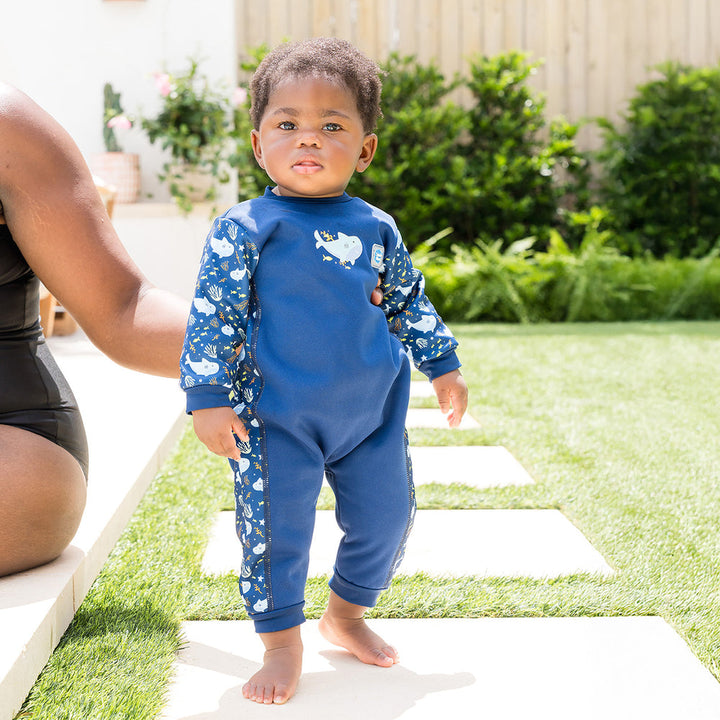 Little one wearing fleece-lined baby wetsuit in navy with sharks themed print.