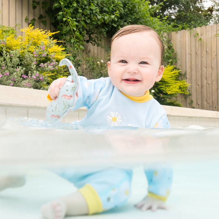 Little one wearing fleece-lined baby wetsuit in baby blue with yellow trims and daisies themed print.