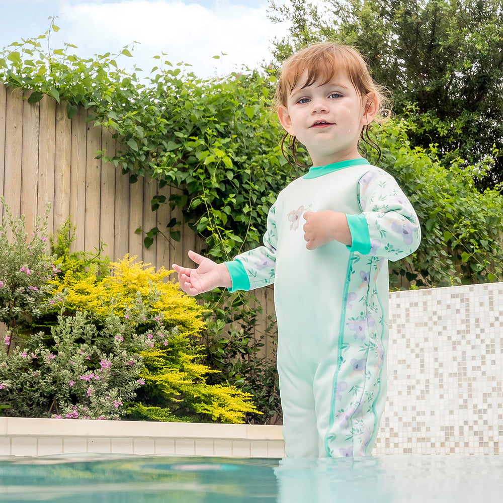 Little one wearing fleece-lined baby wetsuit in light green with mint trims and koalas themed print.
