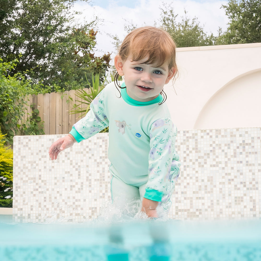 Little one wearing fleece-lined baby wetsuit in light green with mint trims and koalas themed print.