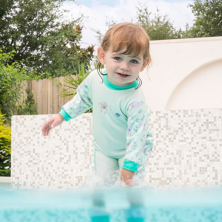 Little one wearing fleece-lined baby wetsuit in light green with mint trims and koalas themed print.