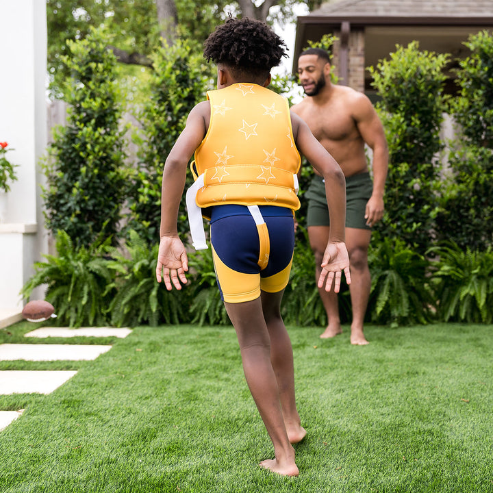 Child wearing neoprene swim vest with non-removable floats in bright yellow, and white stars themed print.