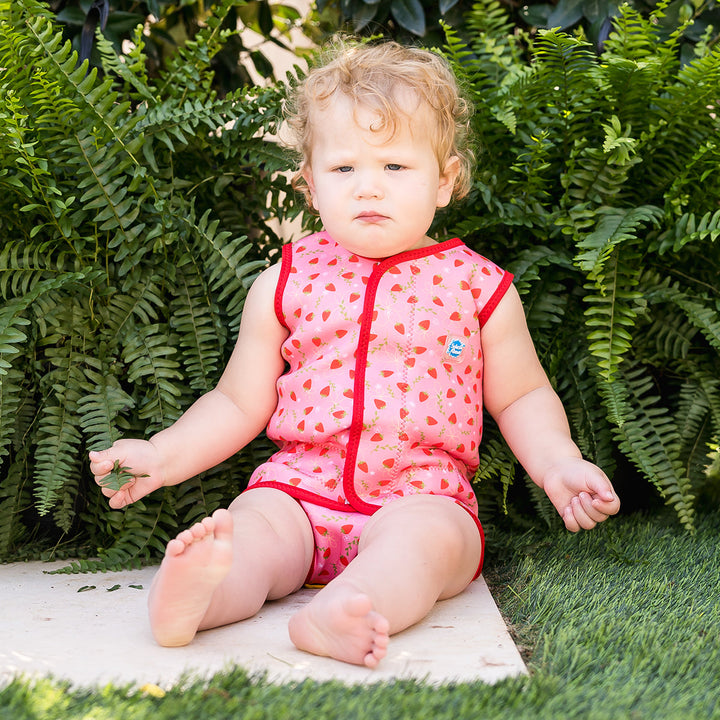 Child wearing neoprene baby wrap wetsuit in pink and red with strawberries themed print.