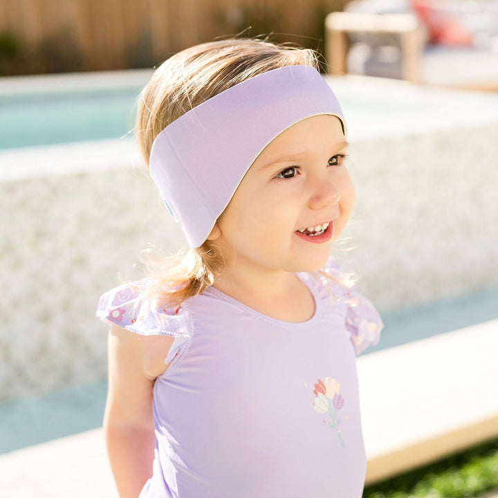 Little one wearing swim ear band in lilac, front