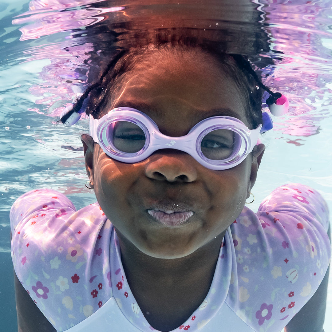 Little one wearing lilac goggles underwater