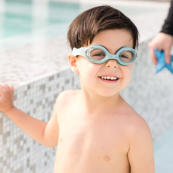 Little one wearing green goggles poolside