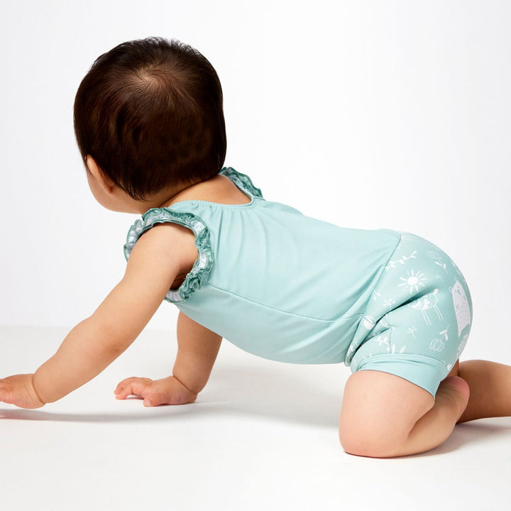 Lifestyle image of child wearing a Happy Nappy Costume in greenish blue featuring animals themed print, including bears, birds and llamas. Back and side.