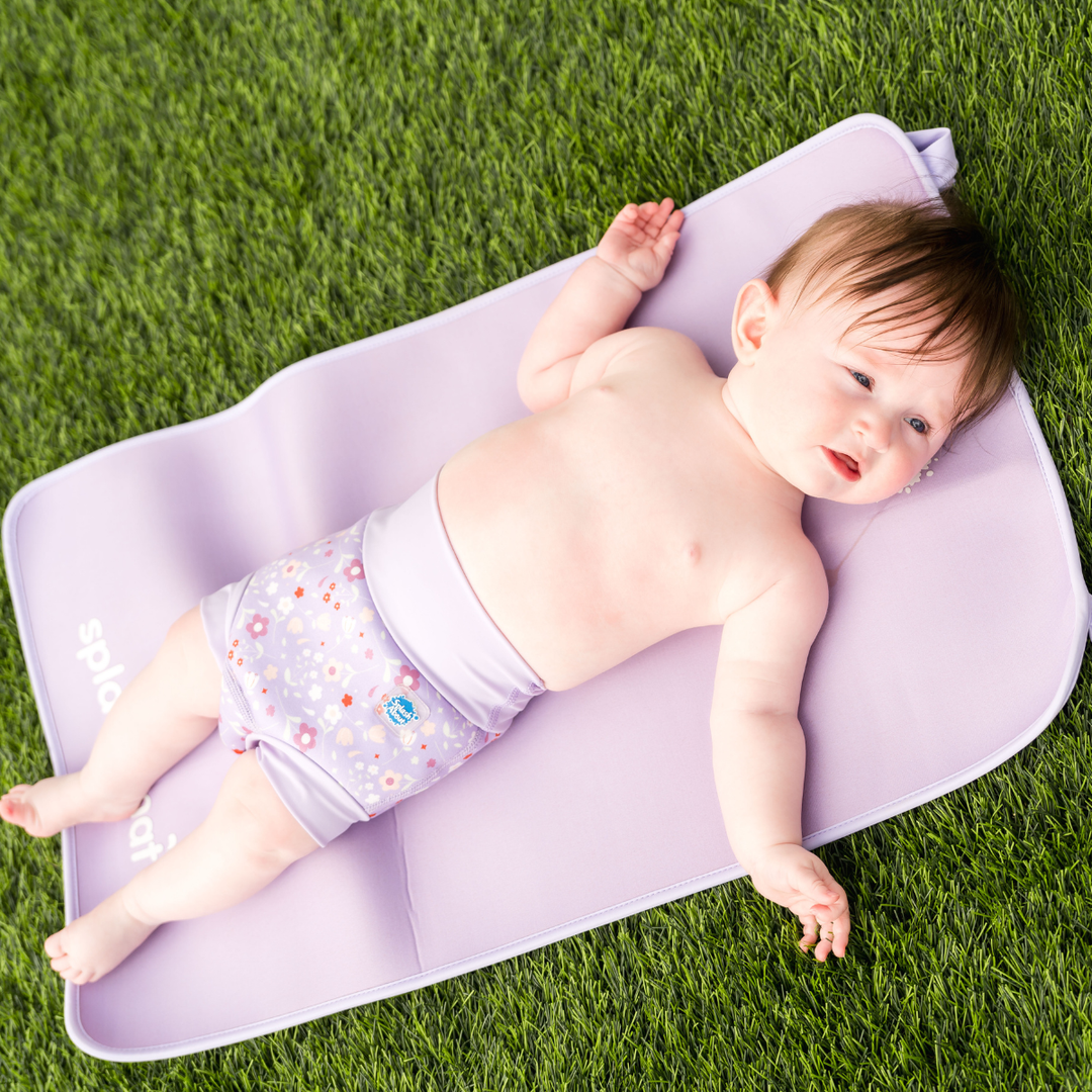 Child wearing reusable swim nappy in lilac and floral themed print. Front.
