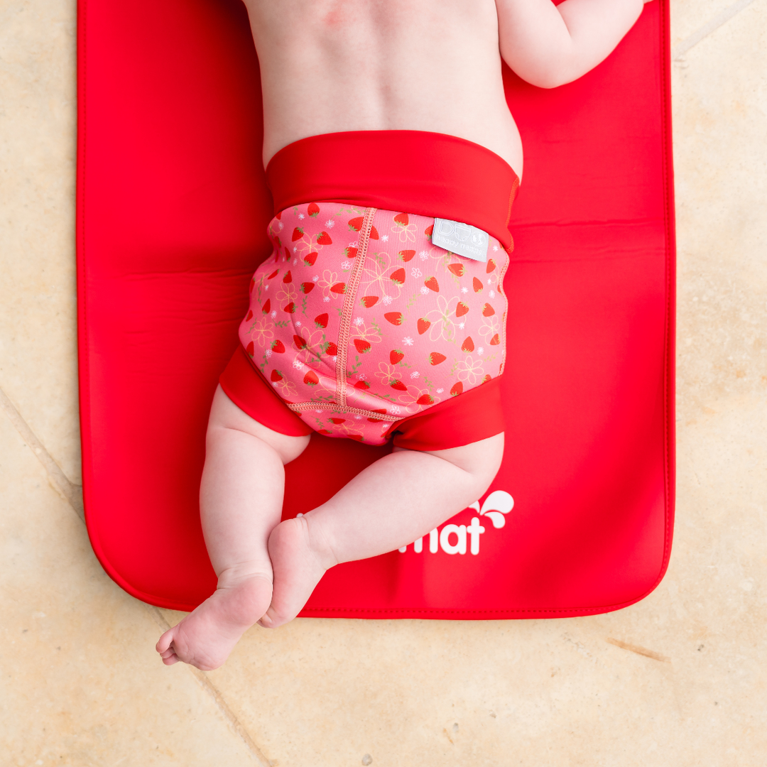 Baby wearing reusable swim nappy in pink with red ribs and strawberries themed print. Back