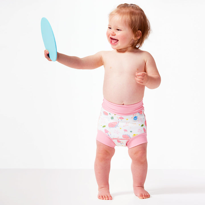 Little one wearing Happy Nappy in white featuring forest themed print. Light pink trims. Side.