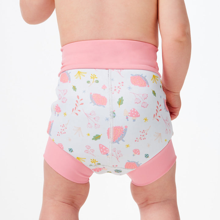 Little one wearing Happy Nappy in white featuring forest themed print. Light pink trims. Back, close up.