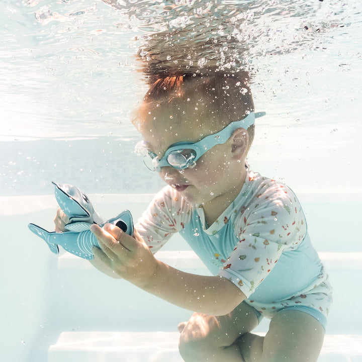 Child swimming in Happy Nappy Sunsuit in light blue and white, and acorns and leaves themed print.