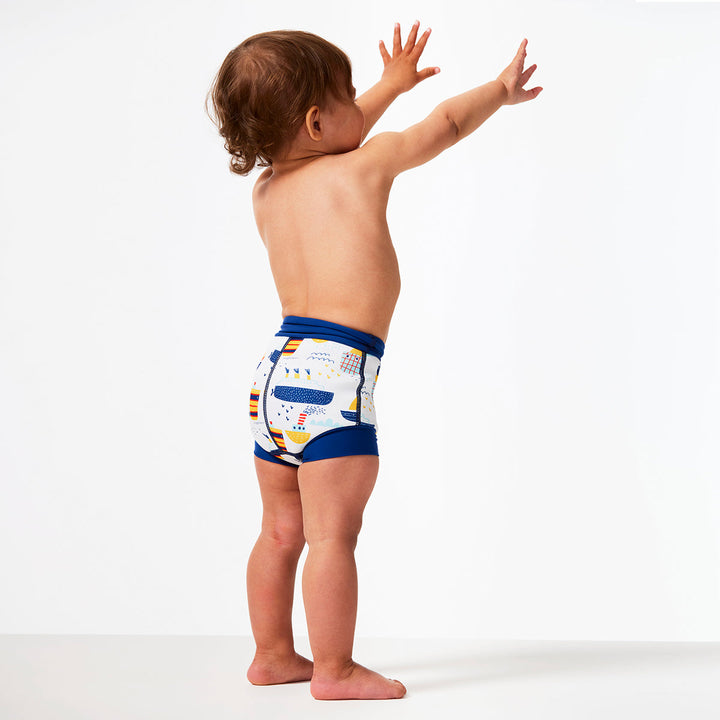 Little one wearing Happy Nappy in white with navy blue trims, featuring boats themed print. Back.