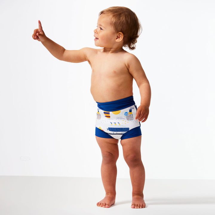 Little one wearing Happy Nappy in white with navy blue trims, featuring boats themed print. Front.