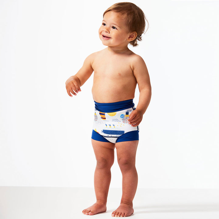 Little one wearing Happy Nappy in white with navy blue trims, featuring boats themed print. Side.
