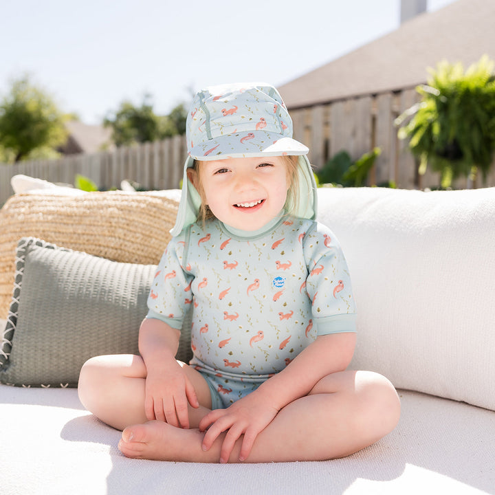Child wearing baby wetsuit with built in swim nappy in light blue with otters themed print.