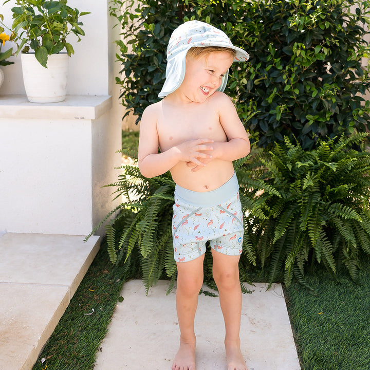 Little one wearing legionnaire style sun hat in light blue, with otters themed print panel. They are also wearing matching jammers.