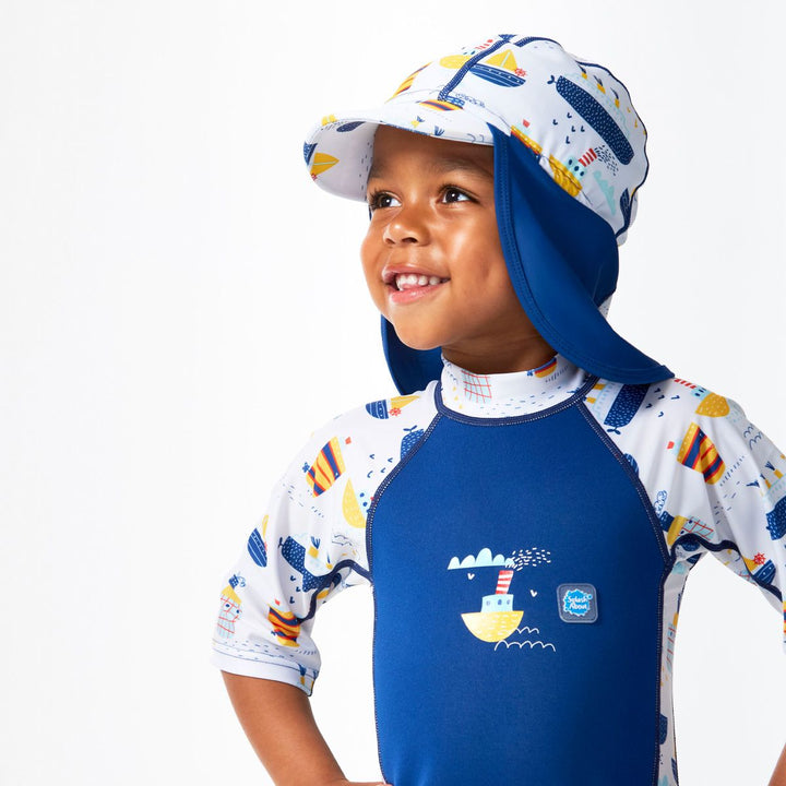 Lifestyle image of child wearing a legionnaire style sun hat in navy and white, with boats themed print panel. Side.