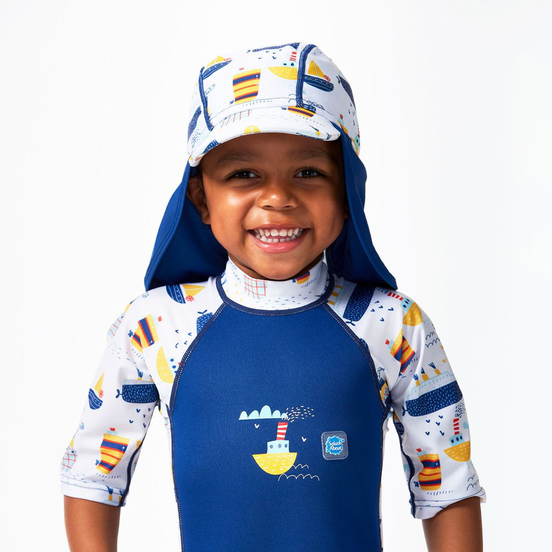 Lifestyle image of child wearing a legionnaire style sun hat in navy and white, with boats themed print panel. Front.