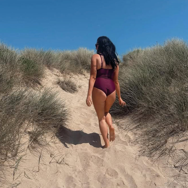 Woman wearing plum swimming costume at the beach.