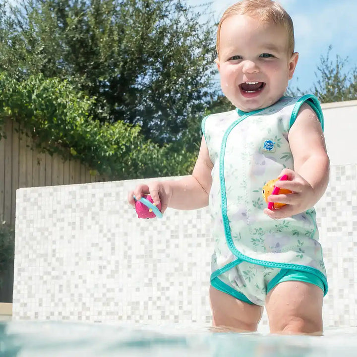 Little one wearing neoprene baby wrap wetsuit in light green and koalas themed print.