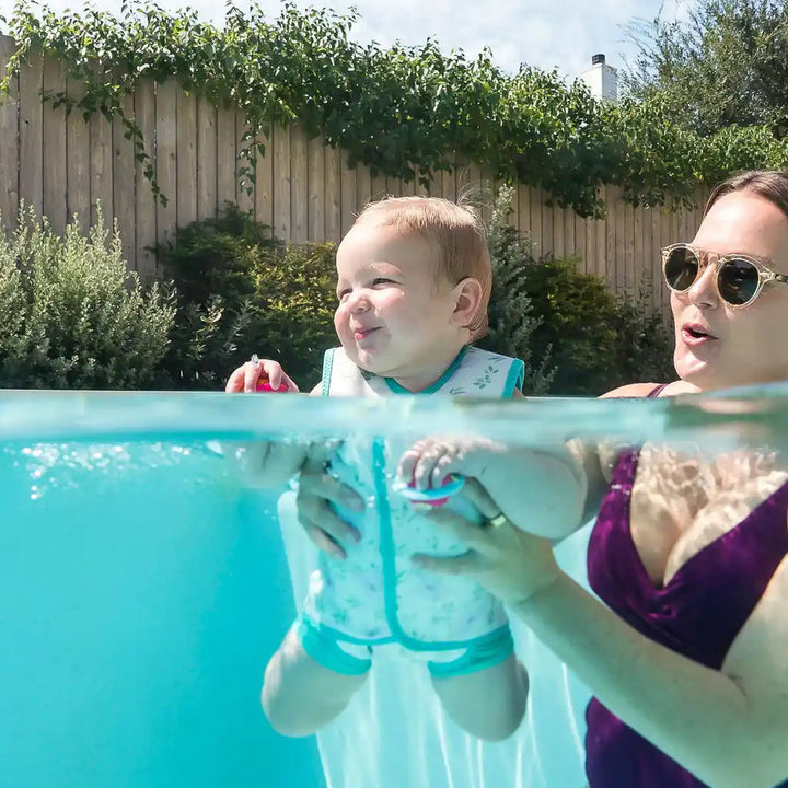 Little one wearing neoprene baby wrap wetsuit in light green and koalas themed print.