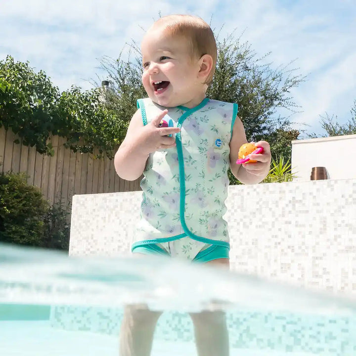 Little one wearing neoprene baby wrap wetsuit in light green and koalas themed print.