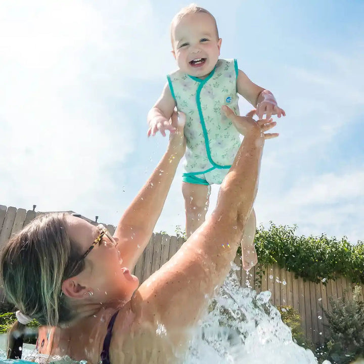 Little one wearing neoprene baby wrap wetsuit in light green and koalas themed print.