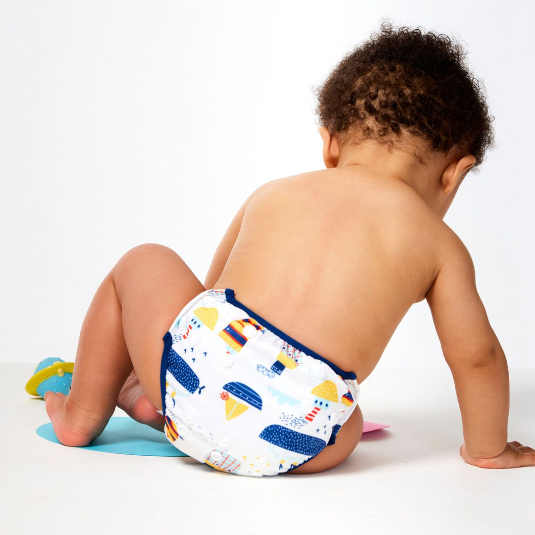 Little one wearing under nappy in white with navy trims and boats themed print. Size adjustable with poppers. Back.