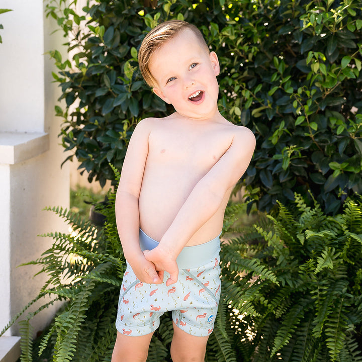 Child wearing neoprene swim shorts in blue with otters themed print.