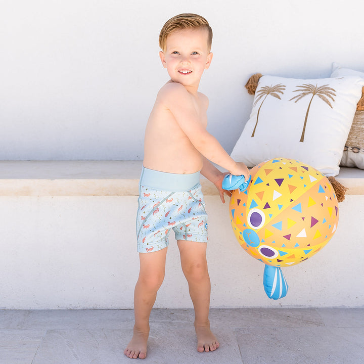 Child wearing neoprene swim shorts in blue with otters themed print.