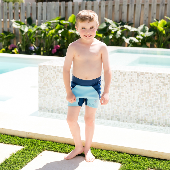 Child wearing neoprene swim shorts in blue and navy.