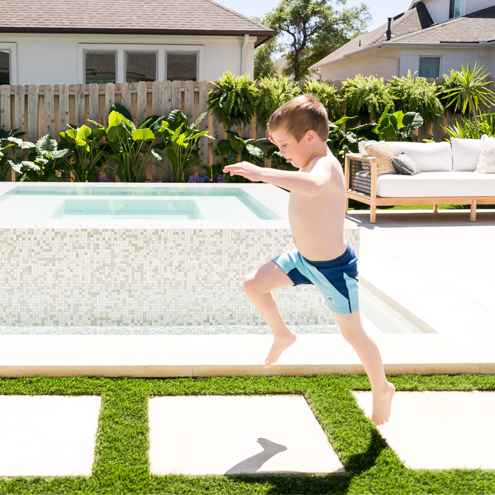 Child wearing neoprene swim shorts in blue and navy. Side.