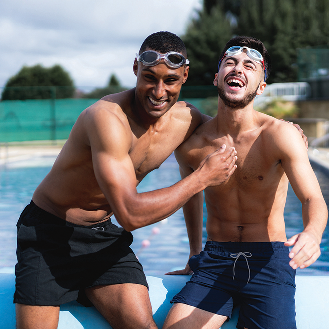 Men wearing navy and black swim shorts by the pool.