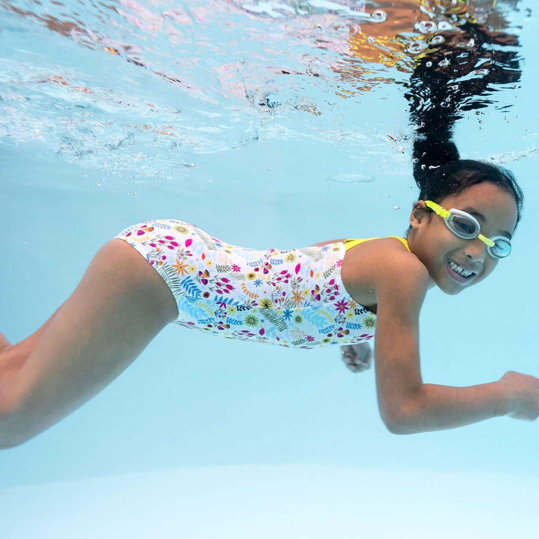 Underwater photo of a girl wearing colourful jungle themed swimsuit with wide straps in bright lime.