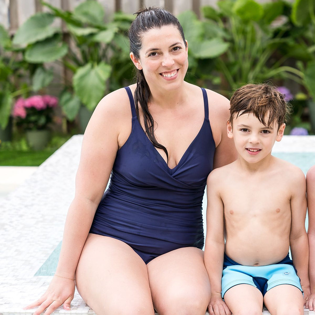 Woman wearing navy blue swimming costume by the pool.