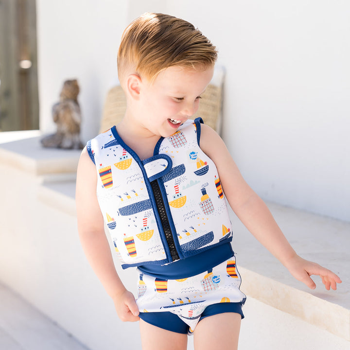 Little one wearing Happy Nappy in white with navy blue trims, featuring boats themed print. Side.