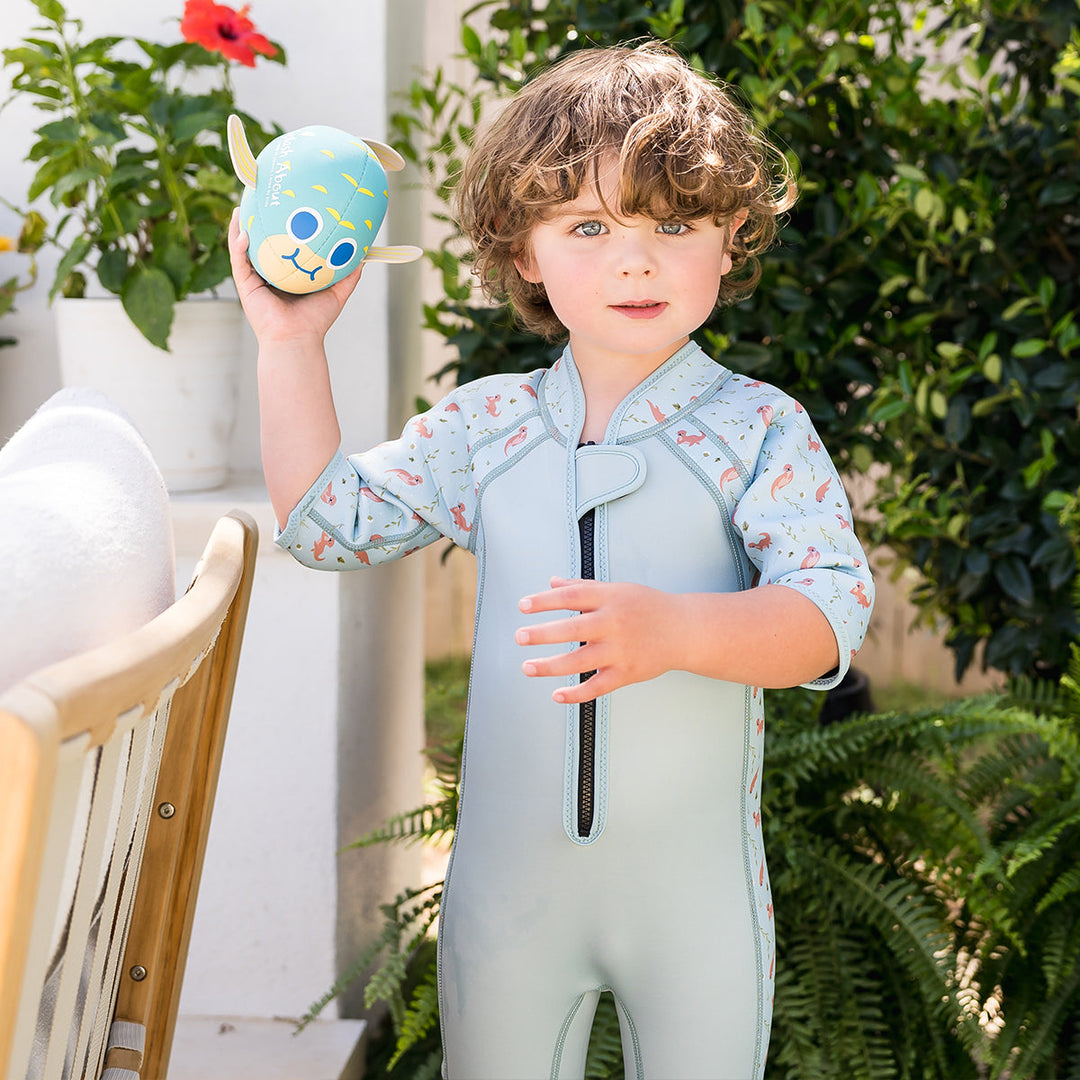 Kid wearing shorty wetsuit in light blue, featuring otters themed print in sleeves and side panels.