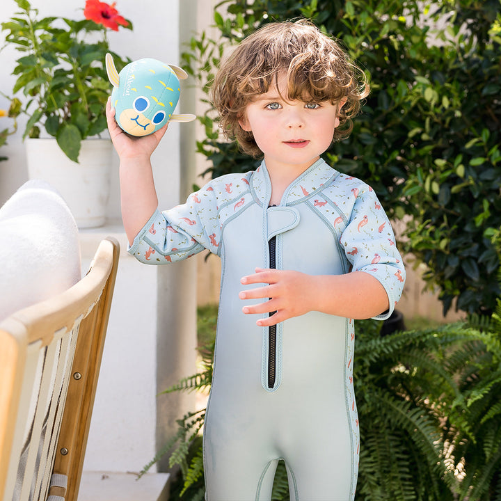 Kid wearing shorty wetsuit in light blue, featuring otters themed print in sleeves and side panels.
