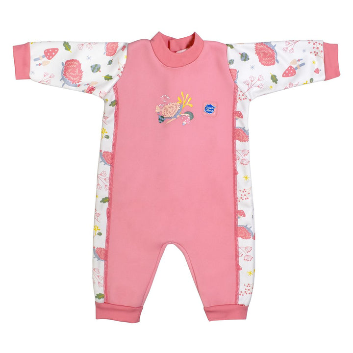 Fleece-lined baby wetsuit in pink and white with pink trims and forest themed print, including hedgehogs, mushrooms, flowers and leaves. Front.