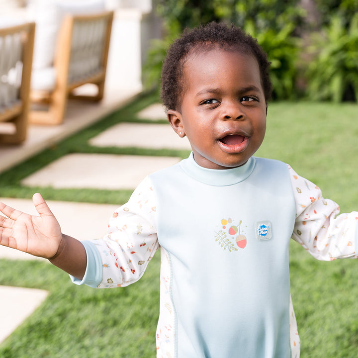 Child wearing acorns themed baby wetsuit in white and light blue.