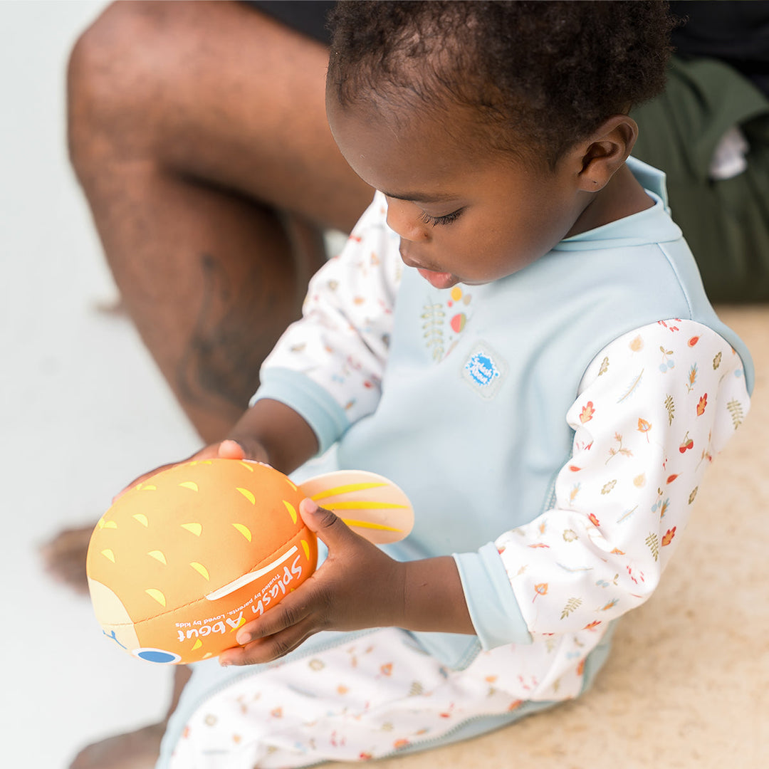 Child wearing acorns themed baby wetsuit in white and light blue.
