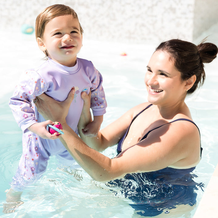 Child wearing floral print themed baby wetsuit in lilac.