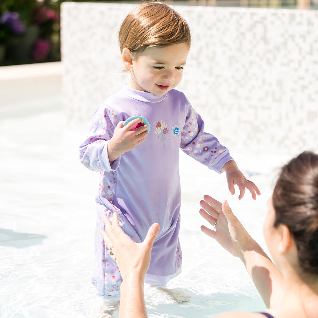 Child wearing floral print themed baby wetsuit in lilac.