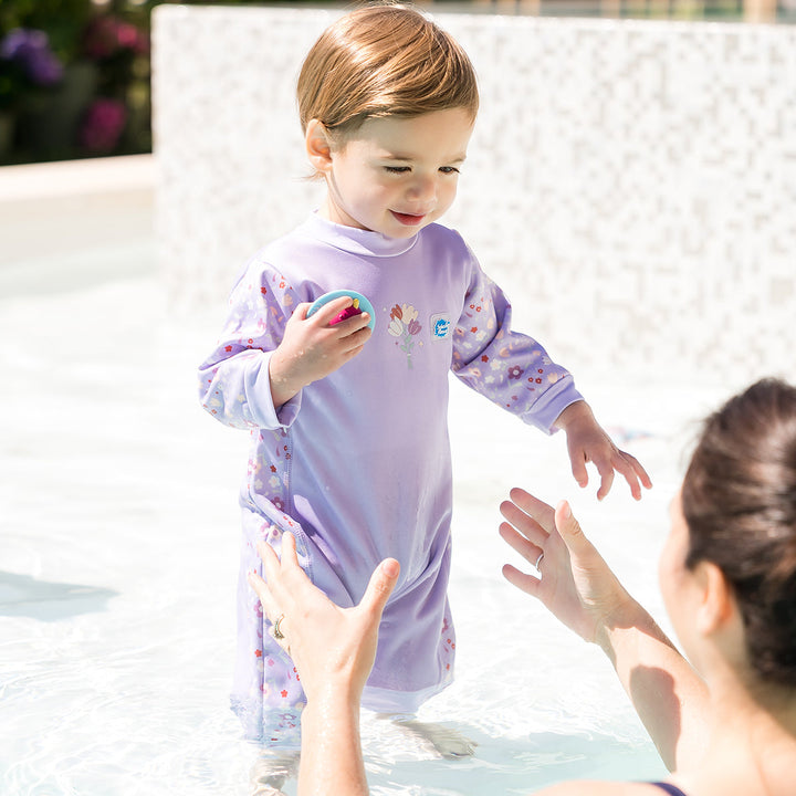 Child wearing floral print themed baby wetsuit in lilac.